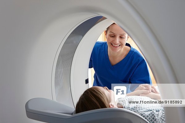 Radiografin lächelt Mädchen im CT-Scanner an