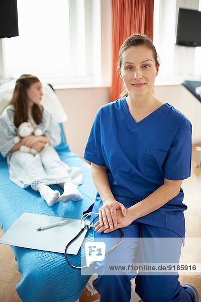 Krankenschwester auf dem Bett des Patienten sitzend