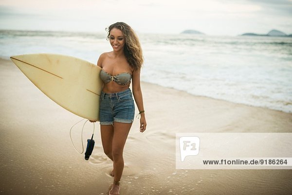 Young woman carrying surfboard on Ipanema Beach  Rio de Janeiro  Brazil