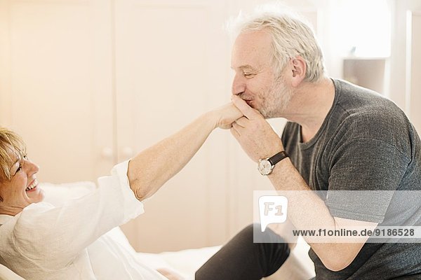 Älterer Mann küsst die Hand einer reifen Frau.
