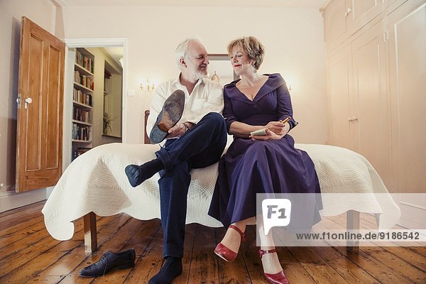 Couple sitting on bed  man putting on shoes