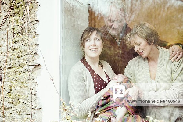 Mutter mit Baby und Großeltern  die aus dem Fenster schauen