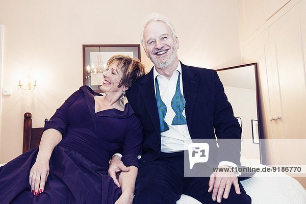 Couple sitting on bed  laughing