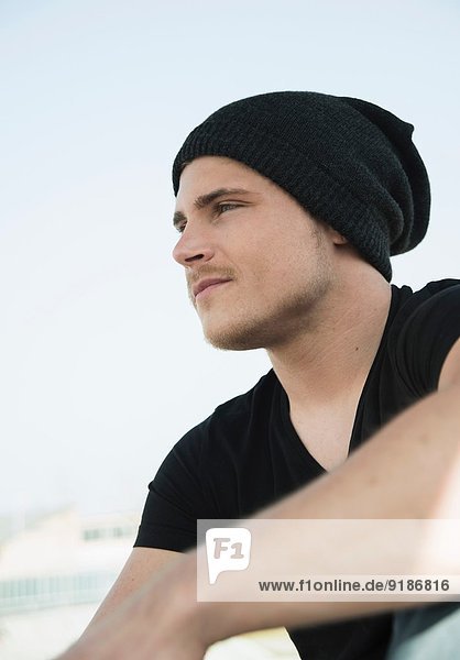 Portrait eines jungen Mannes mit schwarzem T-Shirt und Strickmütze