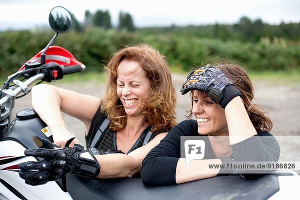 Zwei Motorradfahrerinnen  die sich auf das Motorrad stützen