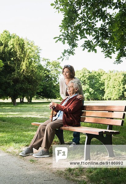 Seniorin auf Parkbank im Park sitzend  mit Enkelin