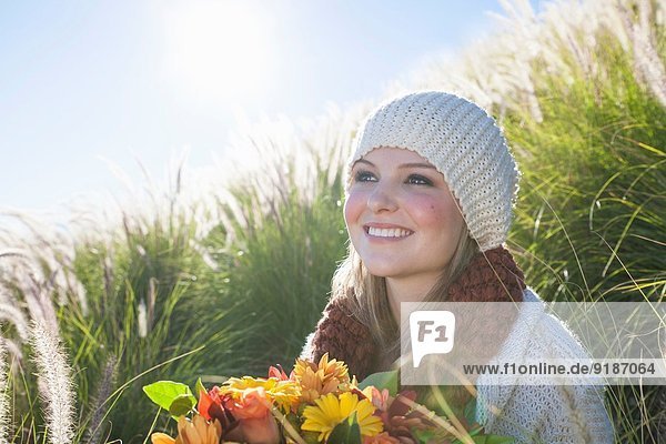 Bildnis einer jungen Frau mit Blumenstrauß im langen Gras