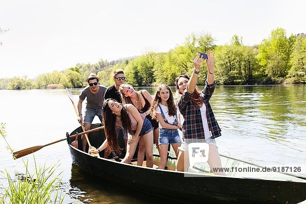 Group of friends in a row boat taking photo of themselves