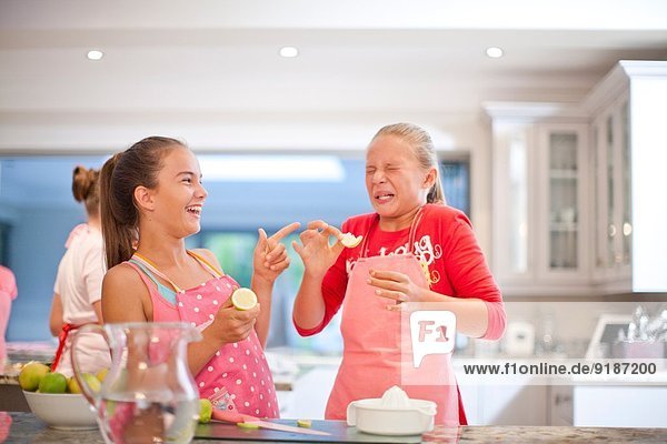 Zwei Teenager-Mädchen probieren saure Zitronen in der Küche