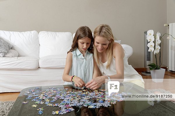 Mutter und Tochter beim Puzzle auf dem Couchtisch