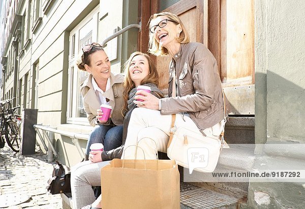 Drei Generationen Frauen trinken Kaffee zum Mitnehmen auf der Straße