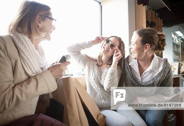 Drei Generationen Weibchen probieren Sonnenbrille im Laden an