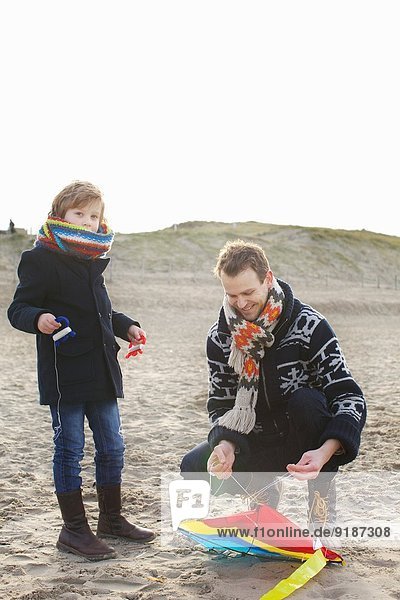 Mittlerer Erwachsener Mann  der den Drachen für den Sohn am Strand vorbereitet  Bloemendaal aan Zee  Niederlande