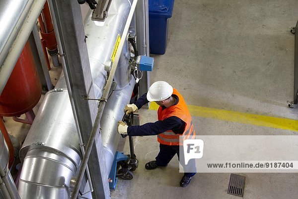 High angle view of technician with pallet trolley in power station