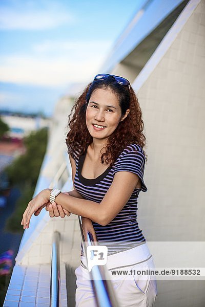 Portrait of smiling woman standing on balcony