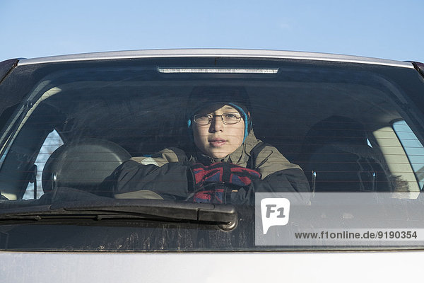 Portrait of confident boy looking through car window