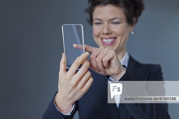 Glückliche Geschäftsfrau berührt auf transparentem Smartphone