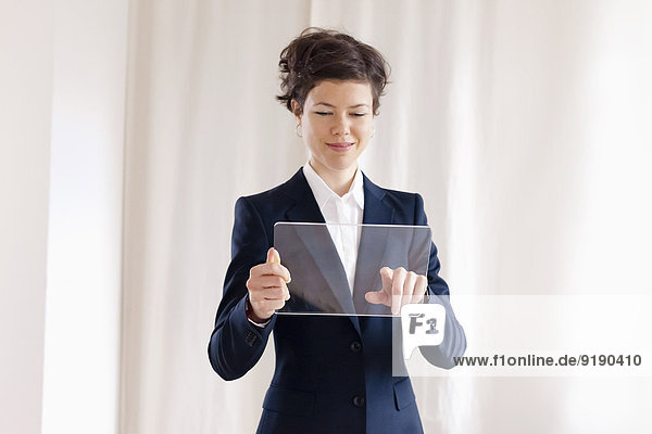 Happy Mid Adult Geschäftsfrau Berühren auf leere transparente digitale Tablette