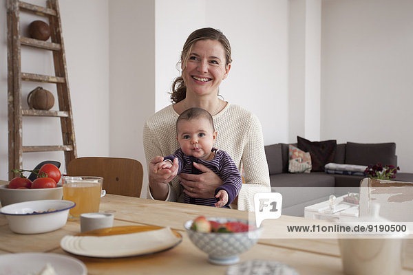 Smiling mother sitting with baby girl at table