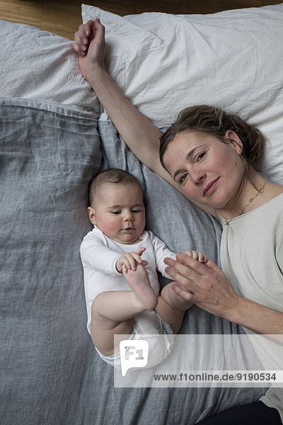 Hochwinkelporträt der Mutter mit Baby auf Matratze liegend