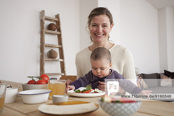 Porträt einer glücklichen Mutter mit einem kleinen Mädchen am Tisch