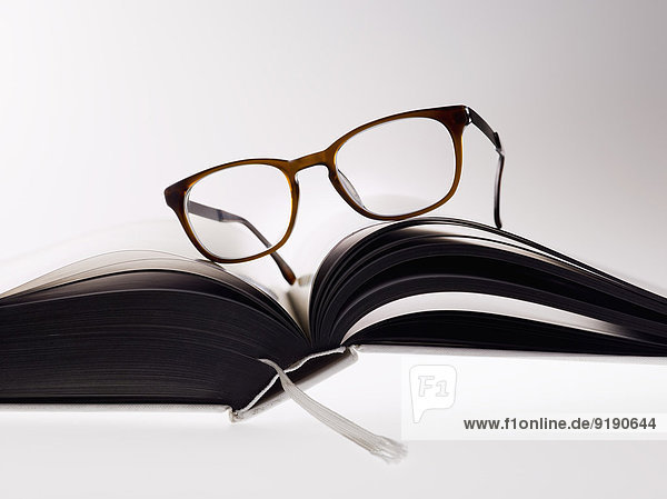 Brille auf Buch über weißem Hintergrund
