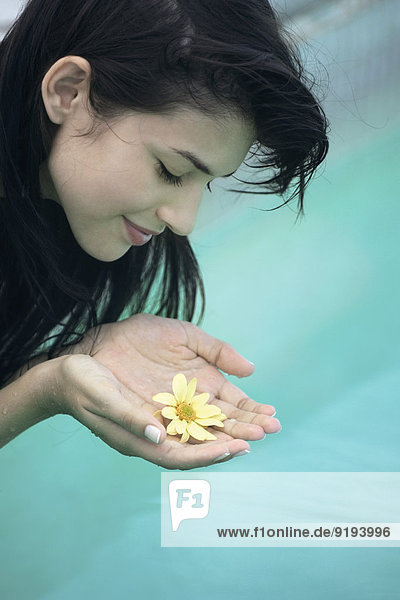 Junge Frau hält die Blume in den Händen.