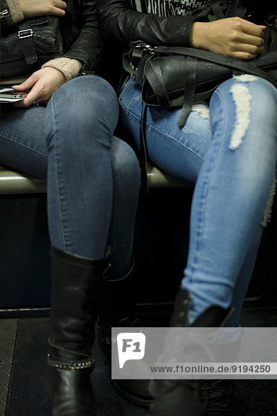 Frauen in Jeans und Stiefeln nebeneinander sitzend