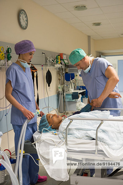 Arzt und Krankenschwester bei einem Patienten im Aufwachraum