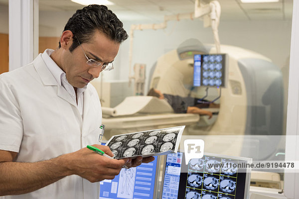 Male doctor examining MRI scan report in medical scan room