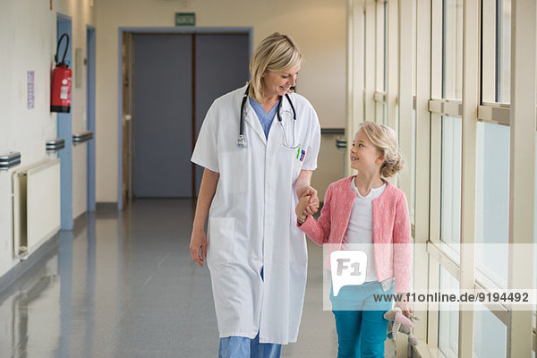 Female doctor walking with a girl in the corridor of a hospital