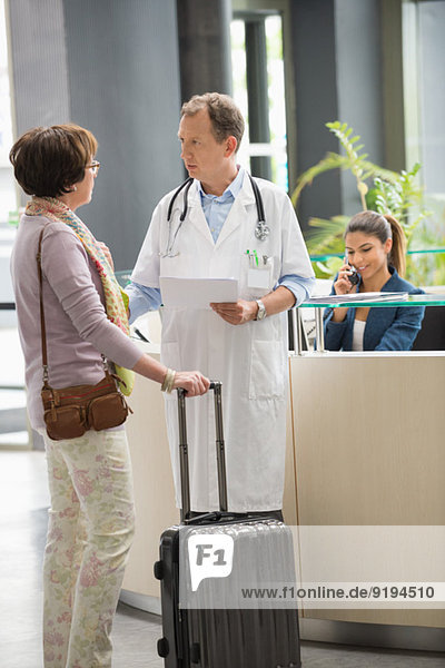 Male doctor discussing with his patient at hospital reception desk