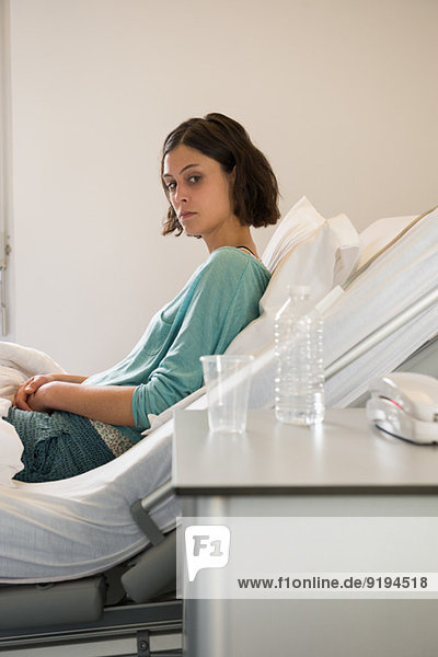 Female depressed patient reclining on the bed in a hospital ward
