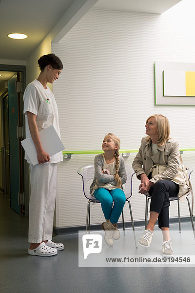 Krankenschwester im Gespräch mit Patienten im Wartezimmer
