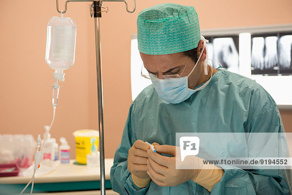 Male surgeon examining medical equipment in an operating room