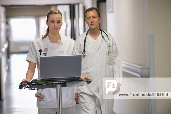 Ärztin und Krankenschwester mit Laptop in einem Krankenhausflur