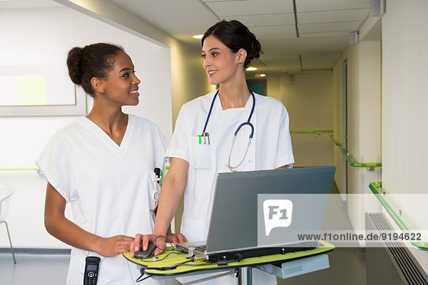 Ärztin und Krankenschwester mit Laptop im Krankenhausflur
