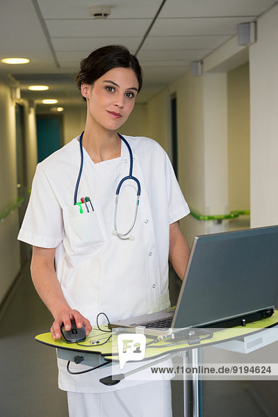 Krankenschwester mit Laptop im Flur des Krankenhauses