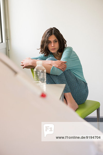 Female depressed patient sitting on the chair in a hospital ward