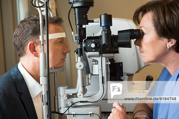 Female optometrist examining man's eyes
