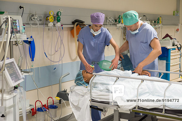 Arzt und Krankenschwester geben dem Patienten Sauerstoff im Aufwachraum