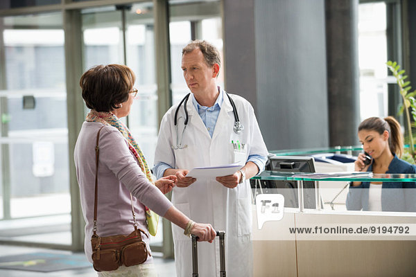 Male doctor discussing with his patient at hospital reception desk