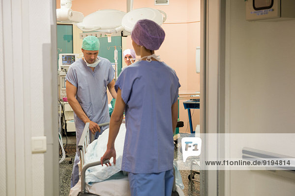 Doctor and nurse moving patient into operating room