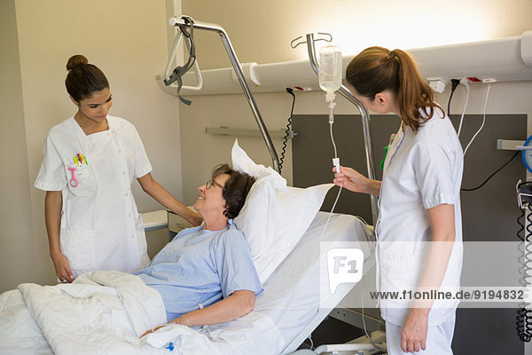 Medical attendants attending female patient on hospital bed