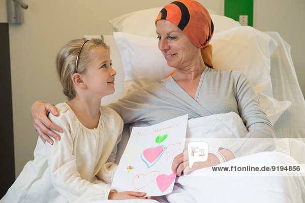 Girl giving greeting card to her illness mother