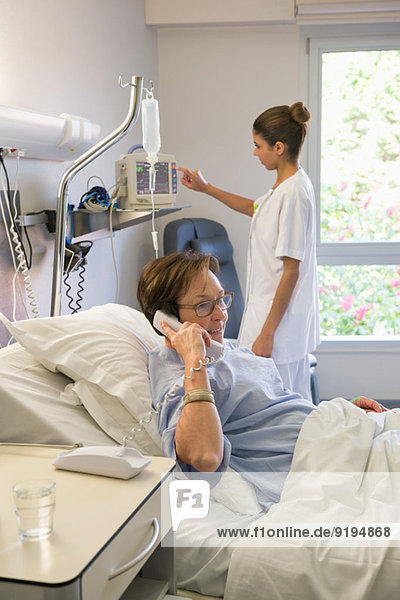 Female patient talking on telephone in hospital bed