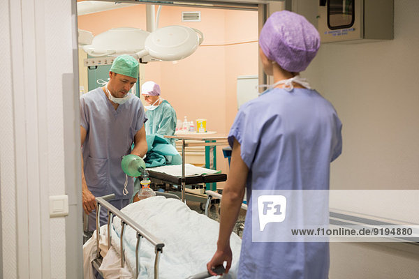 Doctor and nurse moving patient into operating room