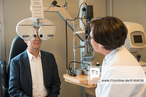 Optometrikerin untersucht Männeraugen