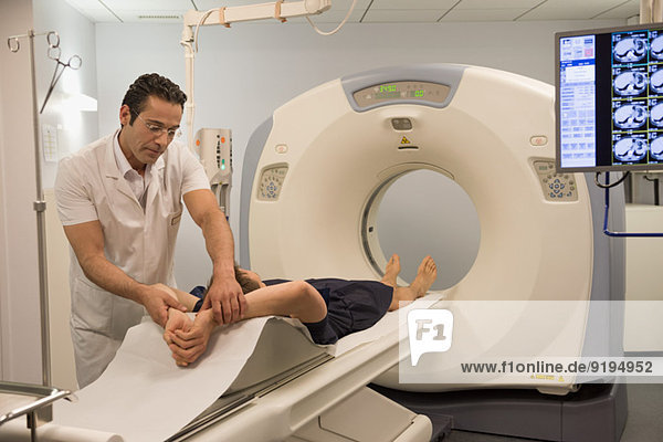 Male doctor preparing patient for MRI scan in hospital