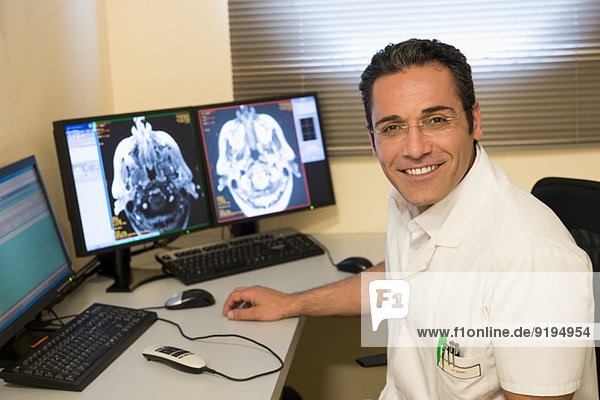 Male doctor examining brain MRI scan on computer